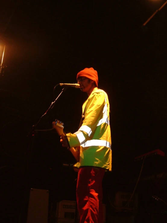 a man in an orange jacket on a microphone
