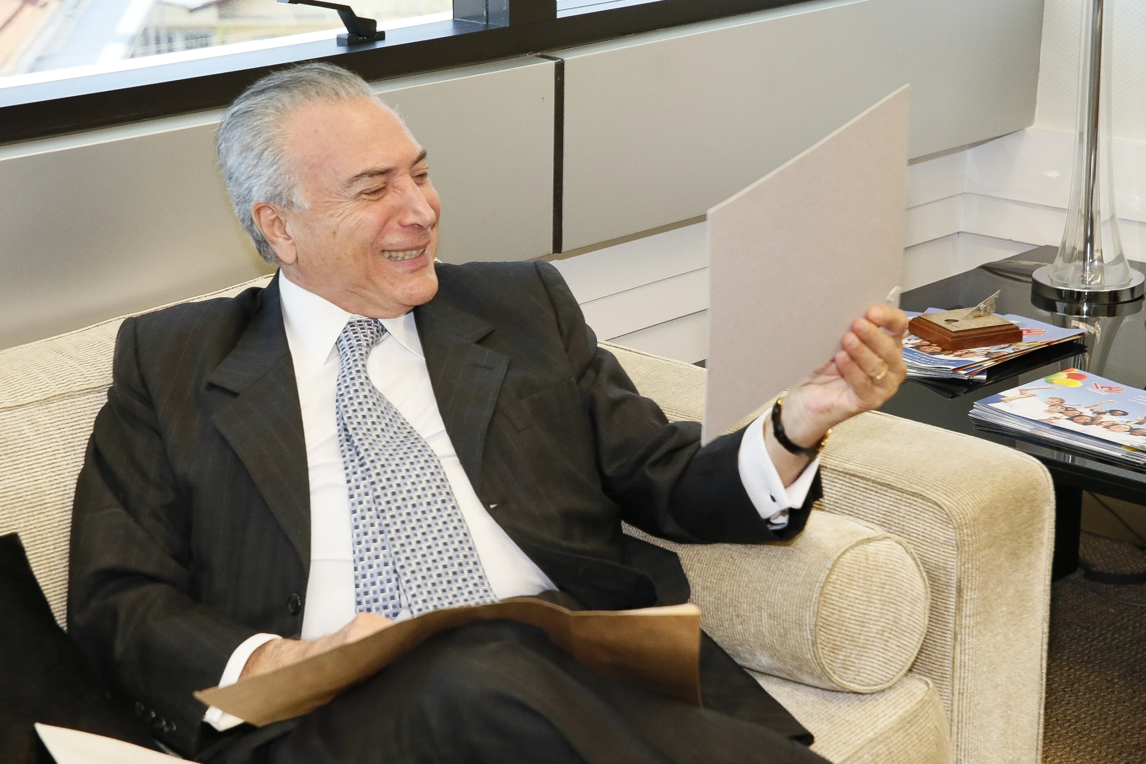 the older man is sitting in a chair with papers and a folder