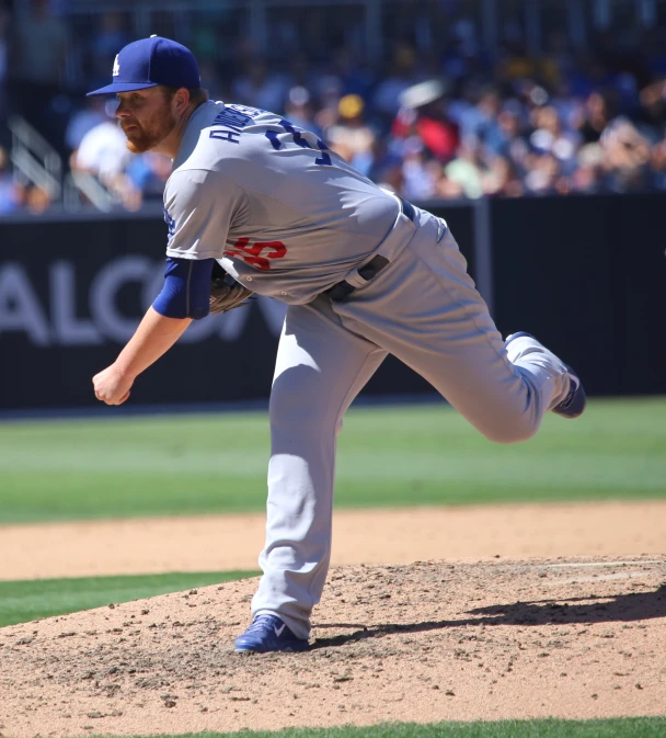 a baseball pitcher with a grey uniform in the process of throwing a pitch