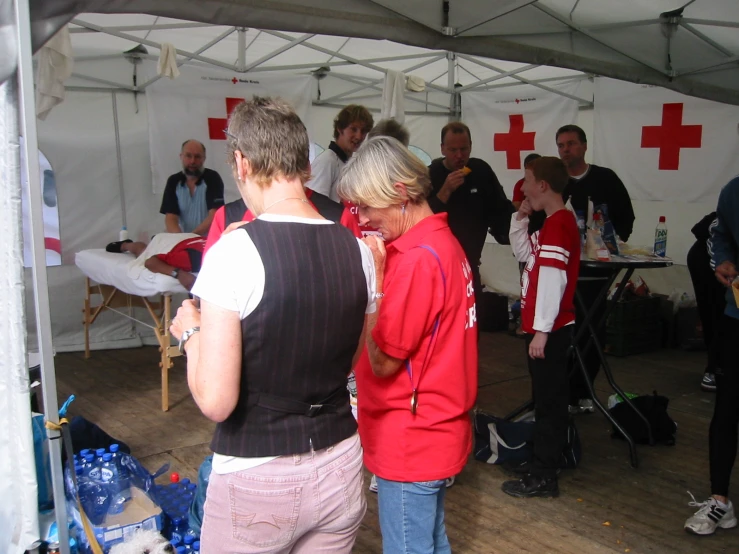 people gather around a tent while one woman speaks on her phone