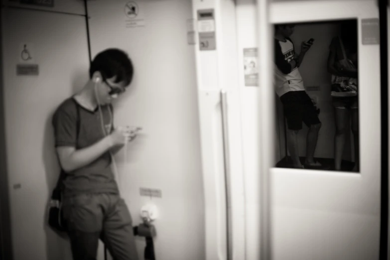 a young man is looking at his cell phone in front of a mirror