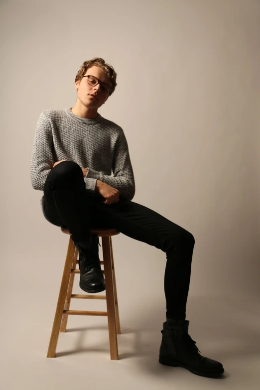 a young man is sitting on a stool