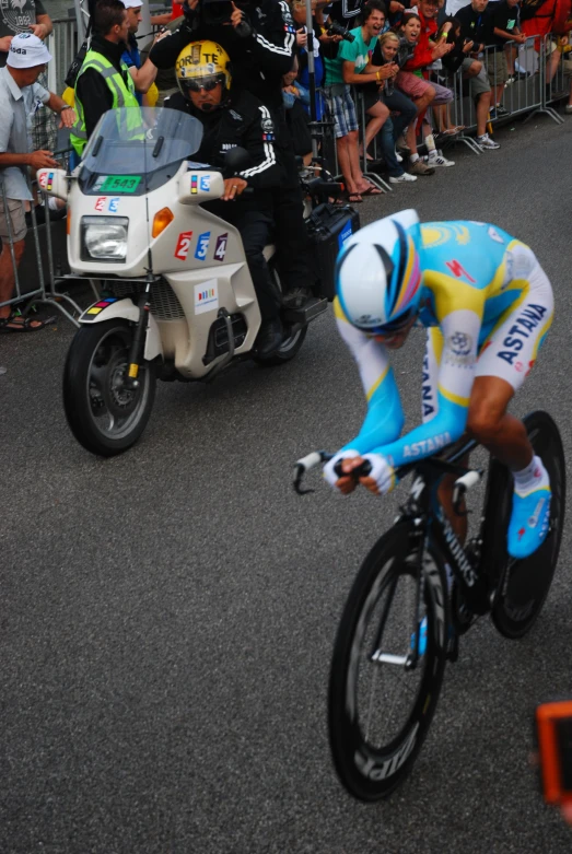 spectators and bicyclists watch the start of a bike race