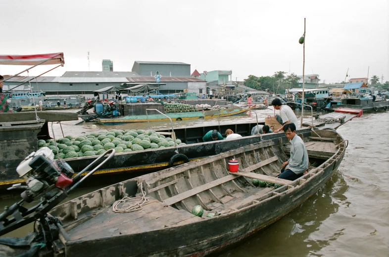 people in canoes pulling produce up the river