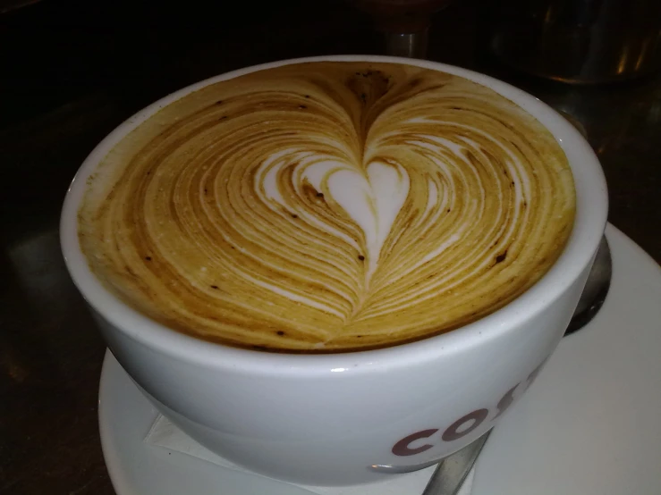 a cup of coffee with a swirly heart in the foam