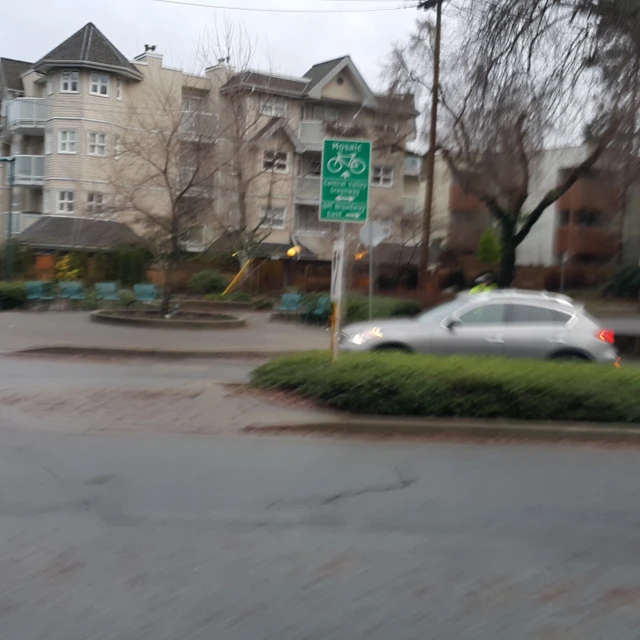 a car driving past an empty residential street in the rain