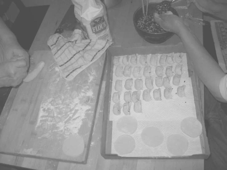 four people are making an iced cookie with icing on top