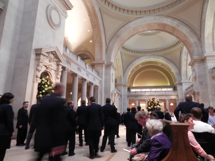 people are walking through a building while one woman sits on a bench