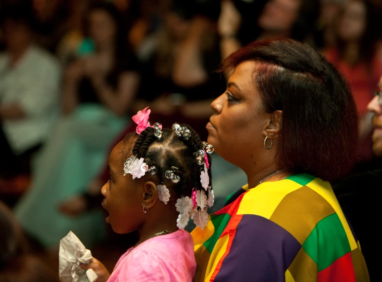 a little girl sitting next to her mom at a wedding