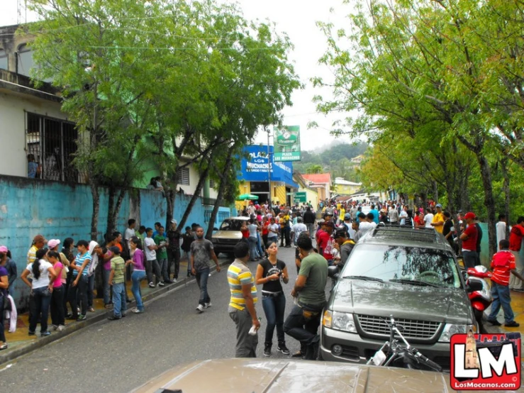 a crowd of people standing in front of cars on a city street