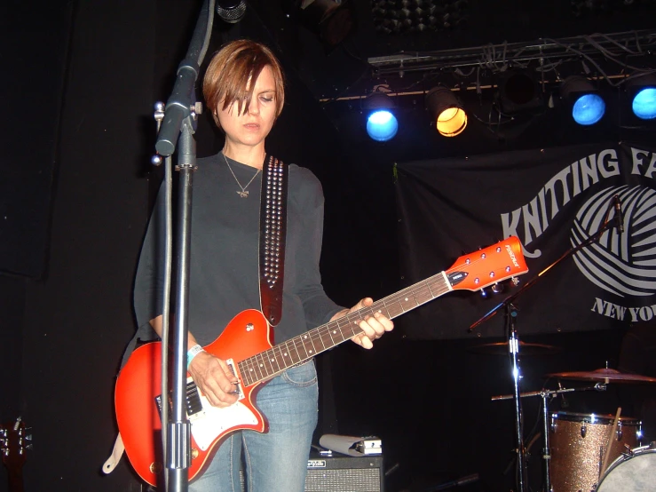 a woman on stage with a red electric guitar