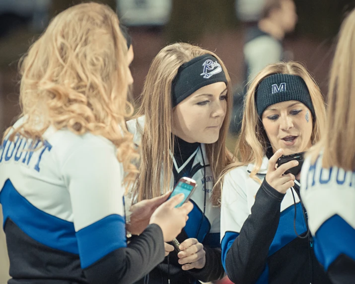 a group of women standing together with one looking at her phone