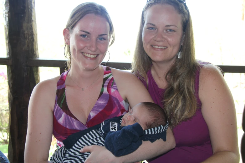 two women holding and holding a baby in their arms