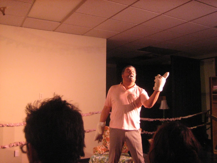 a man wearing a white shirt and beige pants standing in front of a crowd