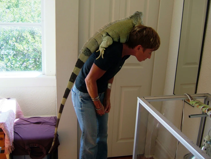 man with big green lizard on shoulders standing by a door