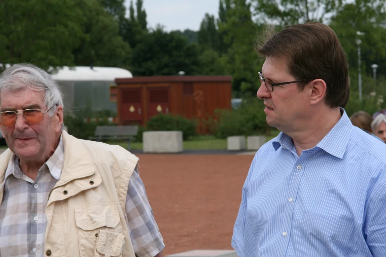 two old men are in an outdoor park near a building