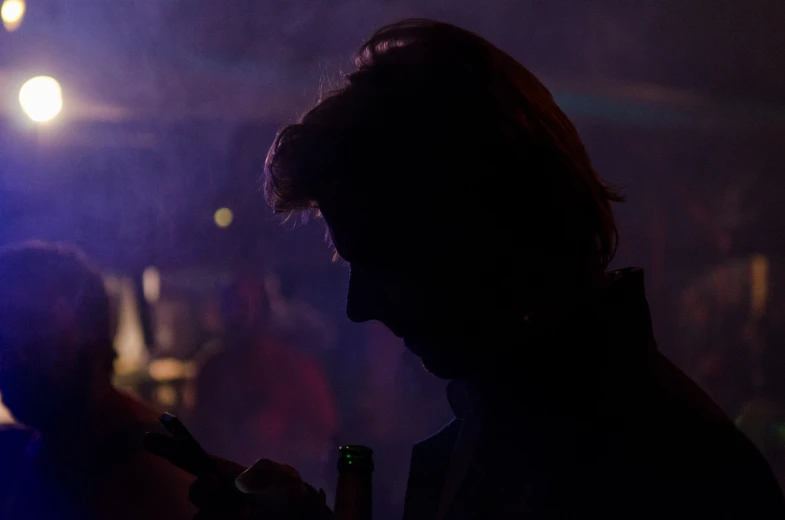 a man at a party drinking and using a cell phone