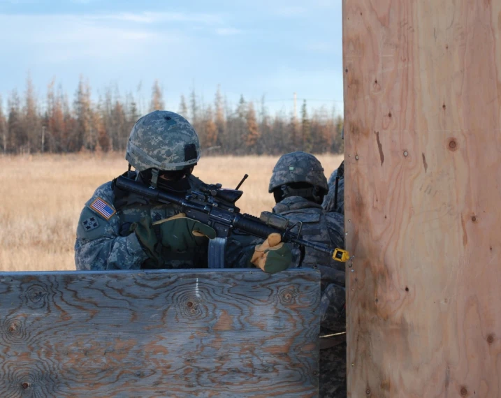 two military men with guns are in an outdoor setting