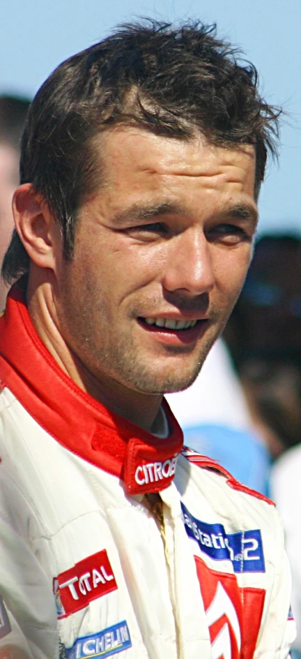 a man with short hair standing in front of a crowd