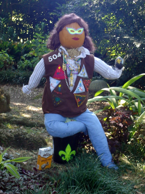 an orange scarecrow sitting on a black stump