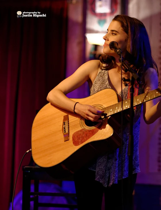 a woman standing on stage playing a guitar