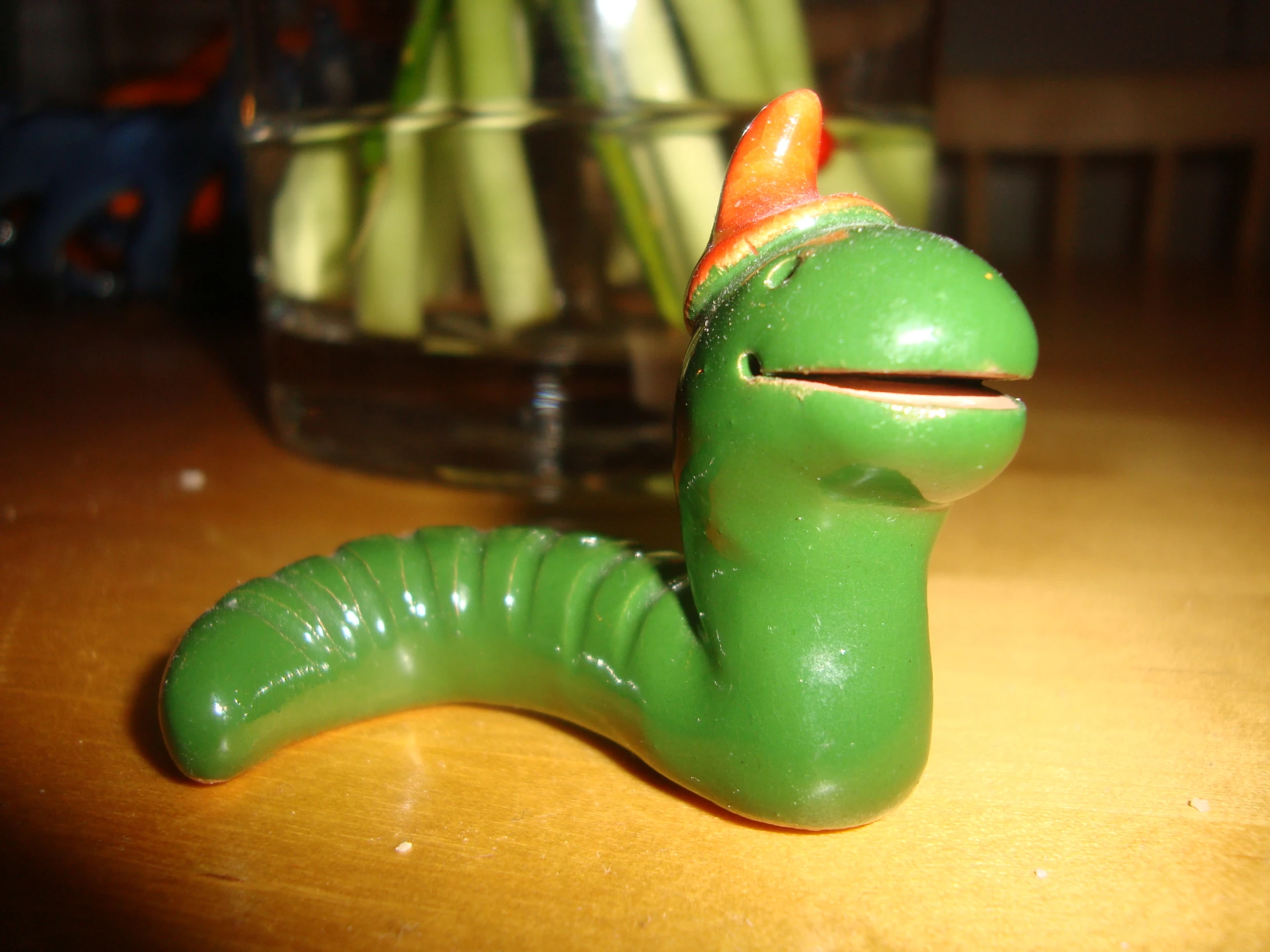 a green toy slug has a red hat on