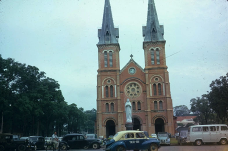 two vintage cars and two classic trucks sit outside an old church