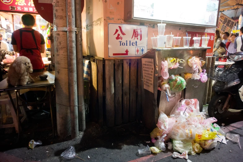 trash is piled near a small store with people nearby