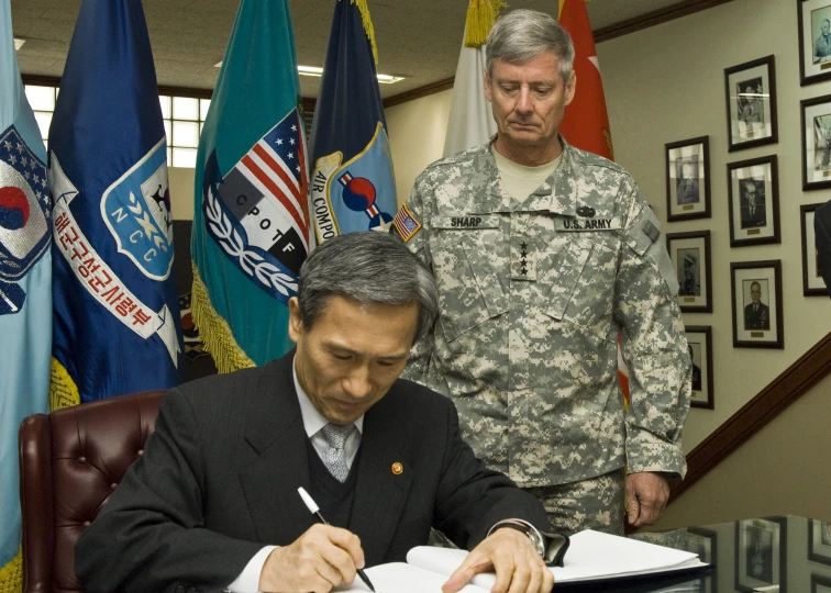 two soldiers signing papers at a desk