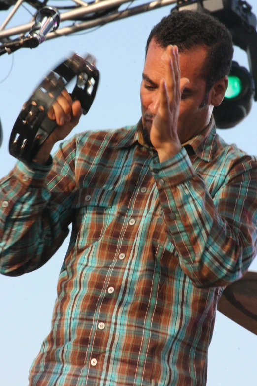 a man in plaid shirt and blue shirt holding microphone