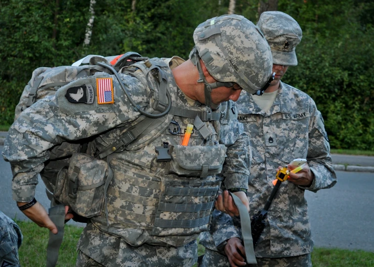 three soldiers with large backpacks are examining soing