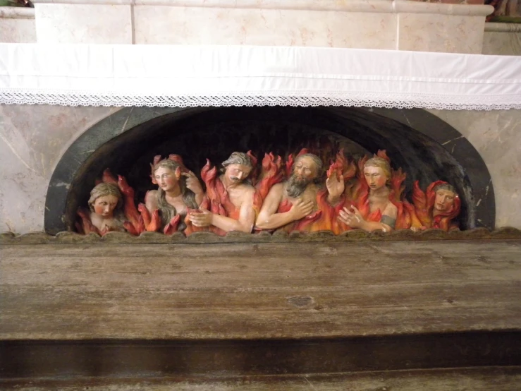 several statues in a fireplace with red flames