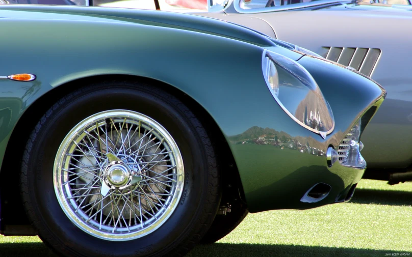 a green vintage sports car with a wheel on the front