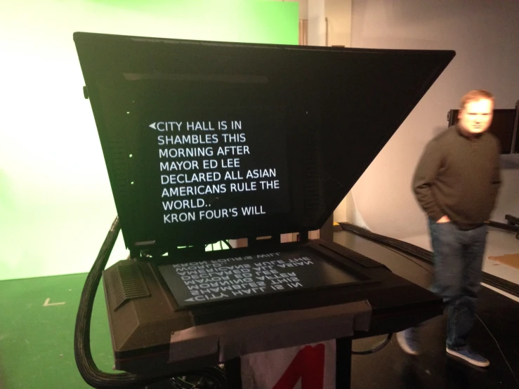 a man standing next to a large monitor in a room