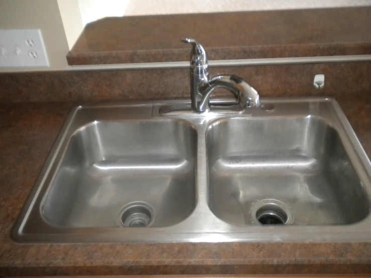 a stainless steel sink with two faucets and soap dispenser