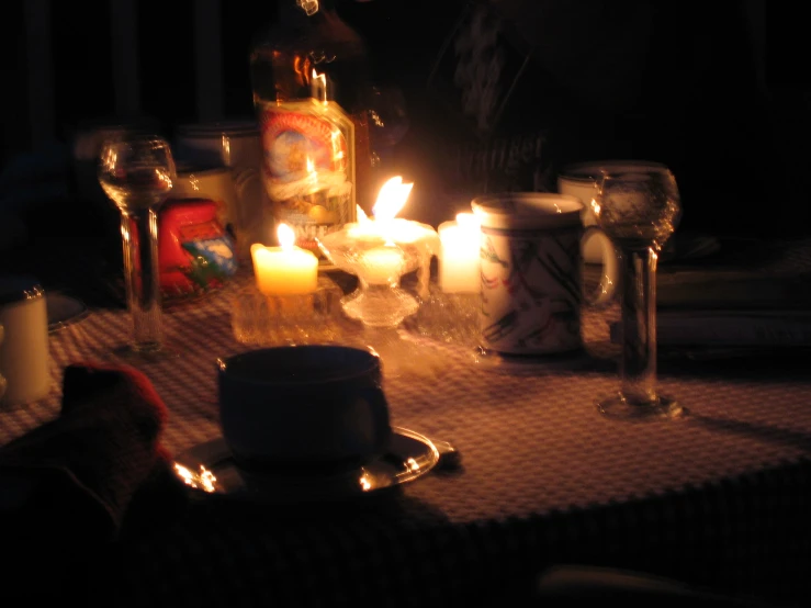 lit candles sitting on top of a table covered in bottles