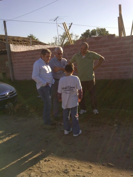 three men and a young child talking by a building