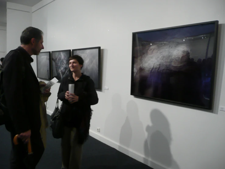 two people in a room with paintings hanging on the wall