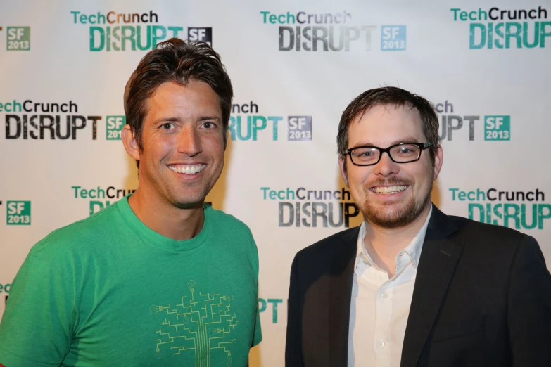 two men standing together in front of a screen at a technology disrupt event