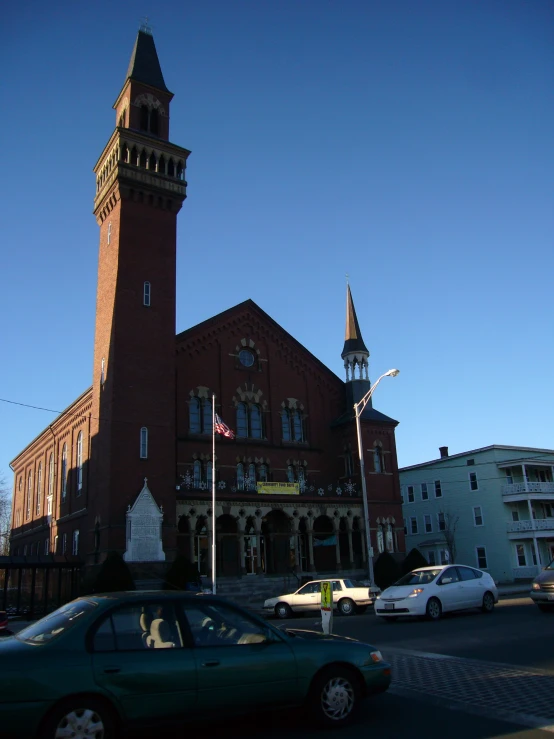 two cars in front of a large building with a clock tower