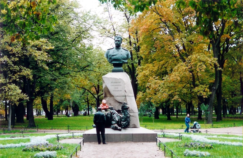 statue of an infant in front of a green park with trees