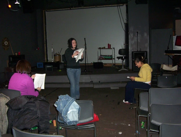 people sitting in chairs and standing near a stage