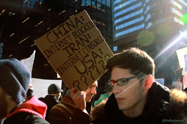 a man holding up a cardboard sign at a protest