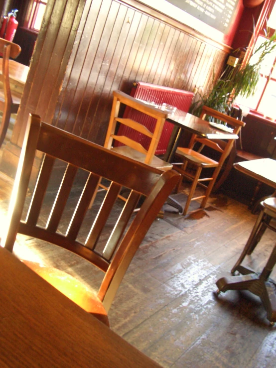 a wooden table sitting inside of a room filled with wooden chairs