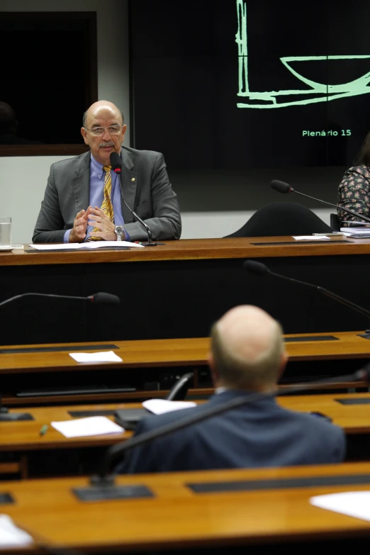 two people in a boardroom and a speaker at a podium