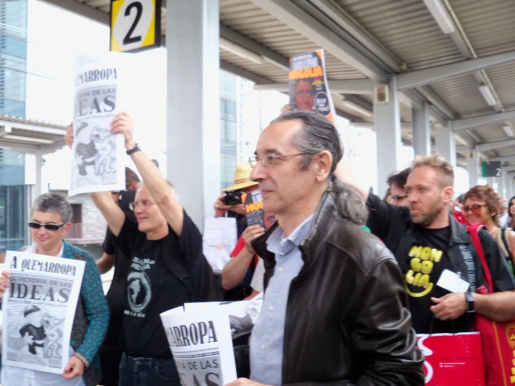 a group of people stand together in front of a building holding signs