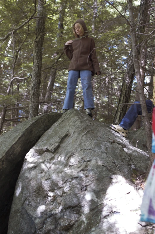 two people standing on top of a rock in the woods