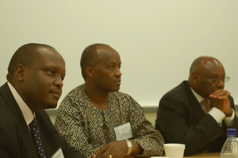 three men at a meeting and one is watching the presentation