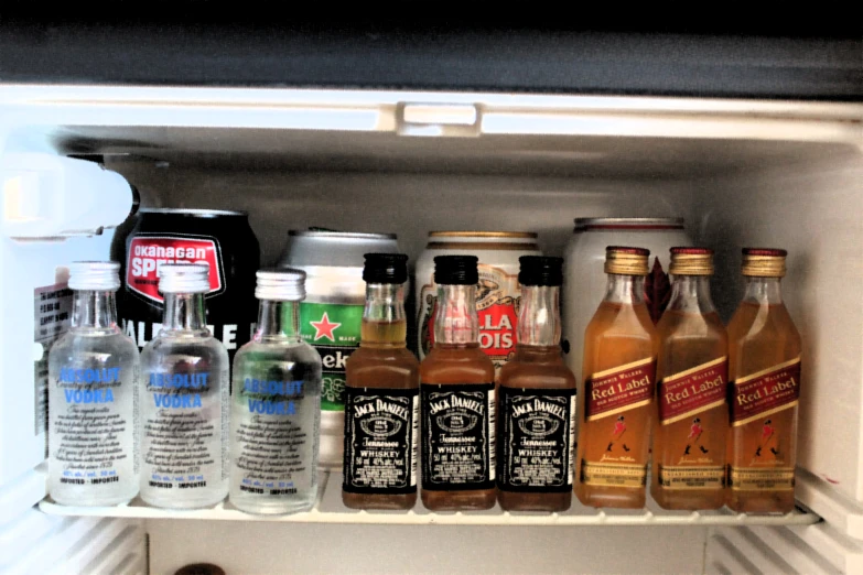an open refrigerator door with bottles of liquor in it