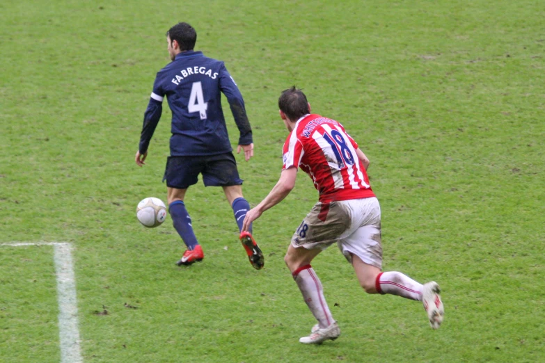 a man runs after the soccer ball with another man